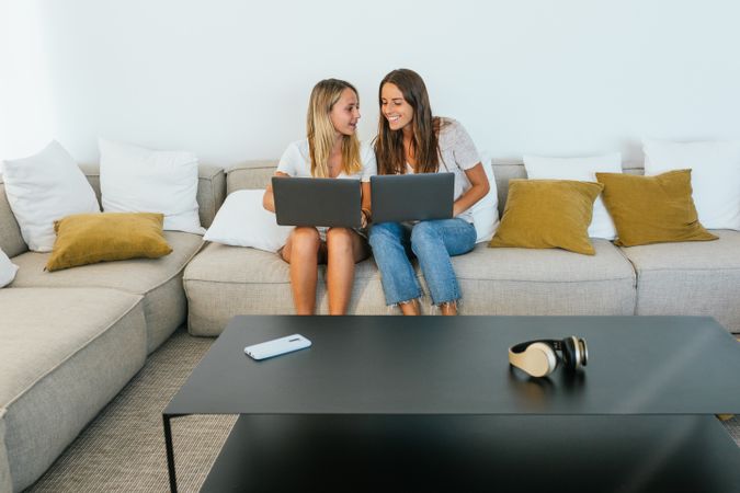Women browsing laptops on couch