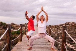 Adult couple meditating on wooden path