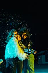 Group of happy female friends lit in green blue light at night with confetti falling