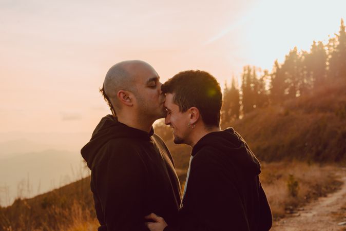 Men hugging and kissing in forest