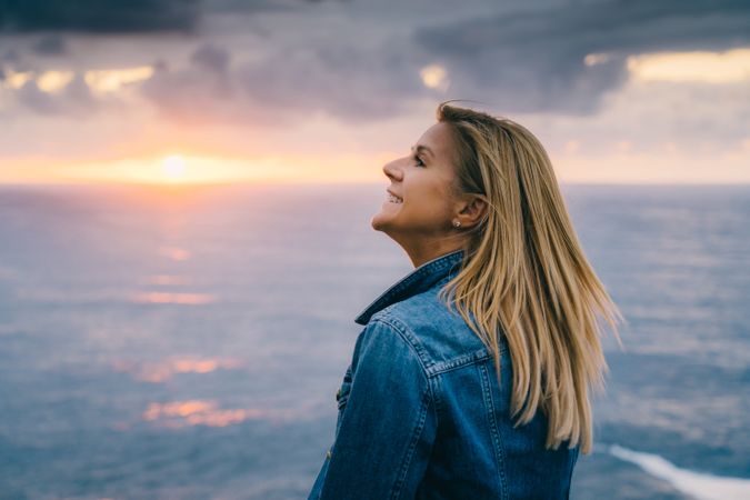 Woman on seashore against dusky clouds
