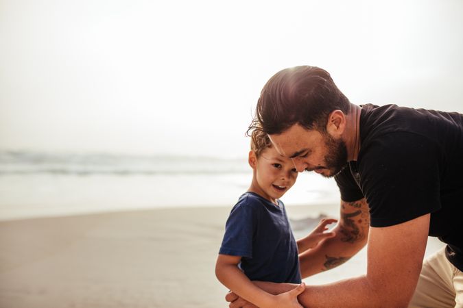 Father adjusting his son’s shirt while at beach