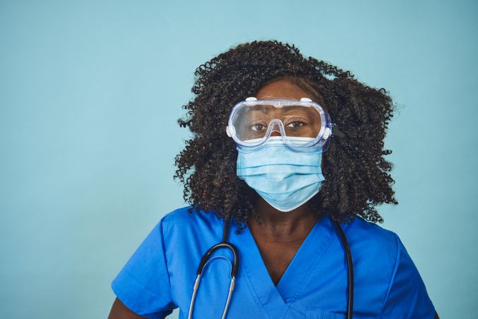 Black female doctor wearing a face mask, protective eyewear, and stethoscope