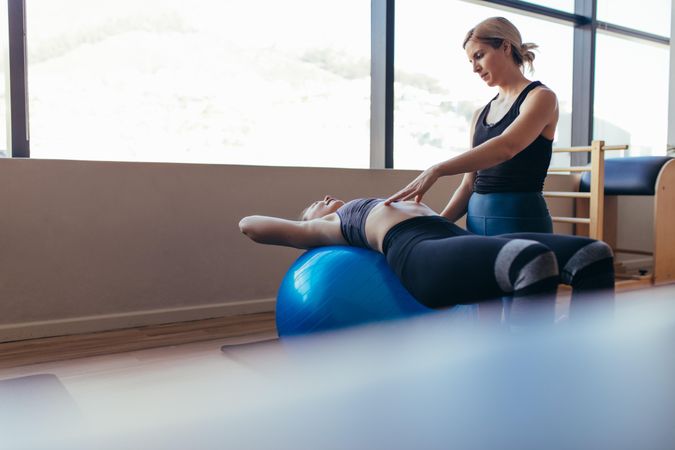 Woman lying with her back on a fitness ball doing pilates training