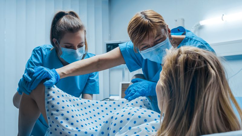 In the Hospital Woman in Labor Pushes to Give Birth, Obstetricians Assisting, Help Spreading Her Legs