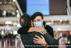 Husband and wife embracing at airport during pandemic 0WRyjb