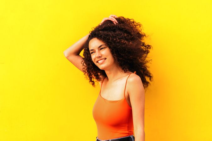 afro latina woman looking aside portrait leaning on a yellow wall