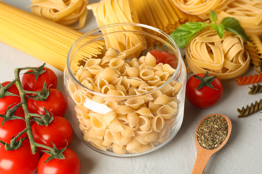 Composition with pasta, tomatoes and spices on bright background, space for text