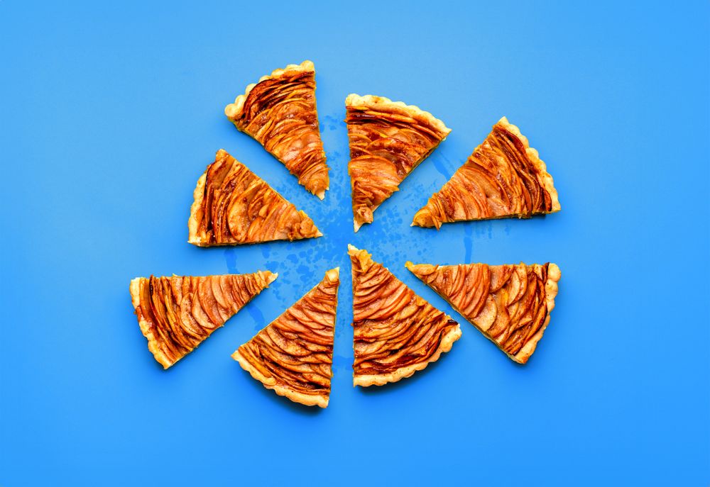Sliced apple pie minimalist on a blue table, above view