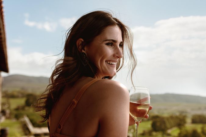 Close up of a smiling woman standing outdoors holding a wine glass