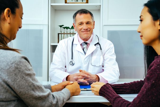 Doctor sharing news with two patients in medical office