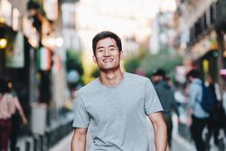 Confident Asian man walking along city street