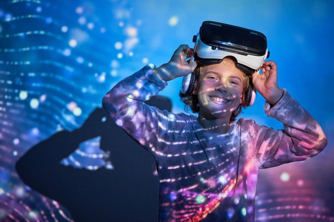 Cheerful child taking off VR headset and smiling at camera