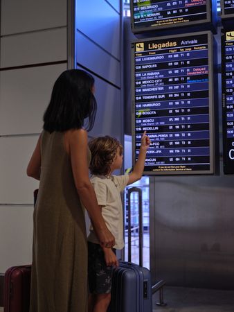 Unrecognizable woman and boy looking at departure time