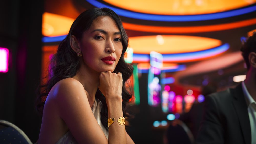 In Stylish Casino Asian Woman Posing Confidently, Looking at Camera, Wearing a Fashionable Cocktail Dress.
