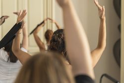 Group of women in a fitness class practicing a graceful, dance-like Pilates or Barre exercise.