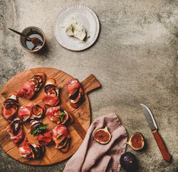 Crostinis with prosciutto, goat cheese and grilled figs, square crop, copy space