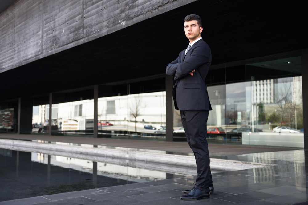 Man standing outside in suit and tie with hands in pockets