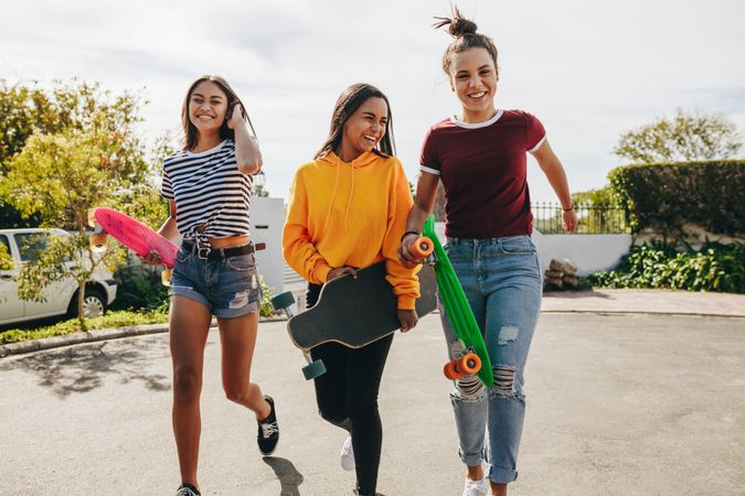 Smiling teenage girls getting ready to skate on the street on a sunny day
