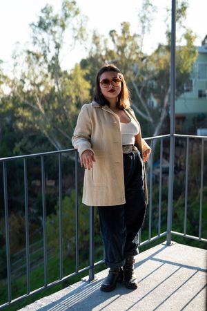 Young woman standing and leaning on patio railing with view behind