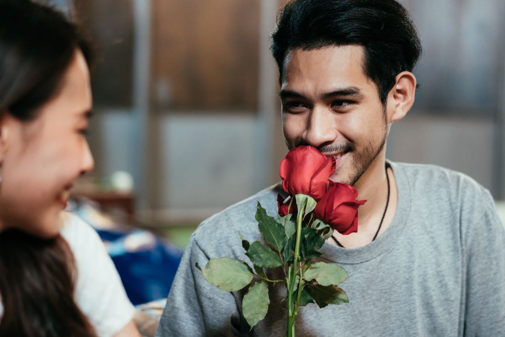 Asian man smelling rose for his girlfriend on date