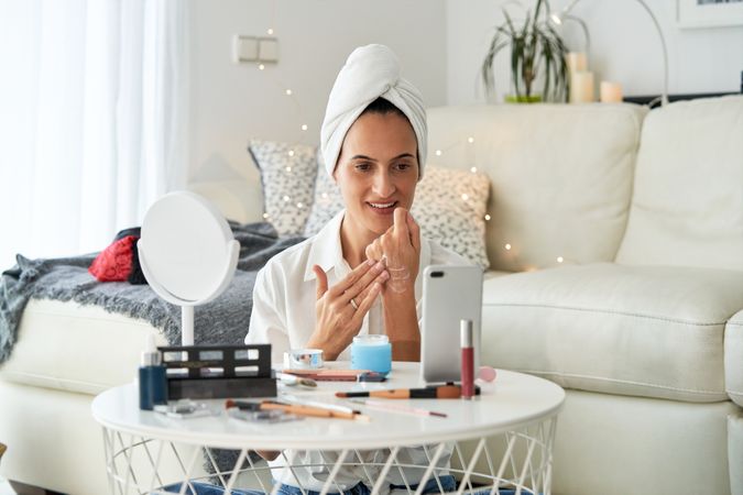 Woman applying cream on hand and recording video