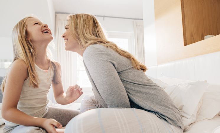 Mother and daughter laughing in bedroom