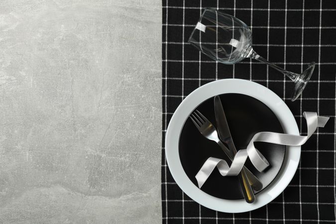 Table setting with napkin, cutlery and wine glass on gray background
