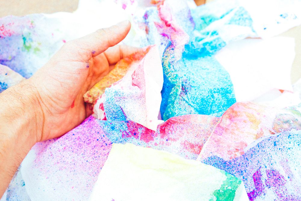 Person taking colorful crumpled sheets of paper on table
