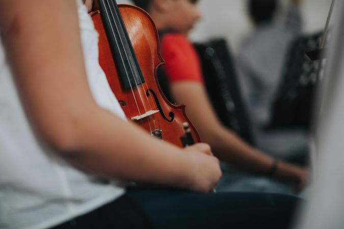 Students sitting in a row and holding violin