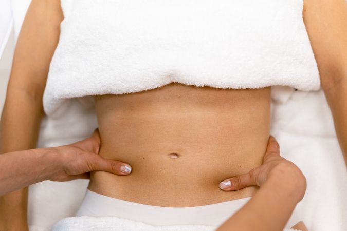 Massage therapist working on a female client’s abdomen