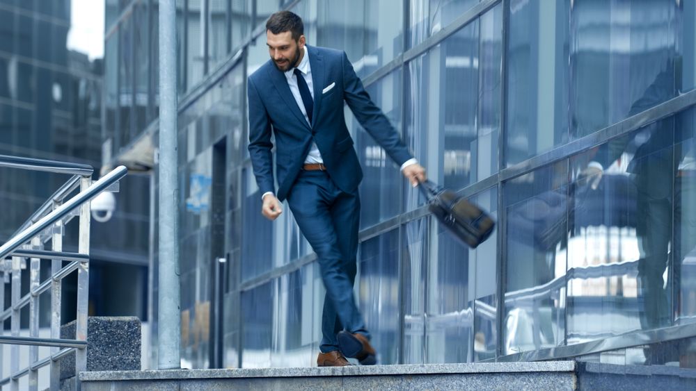 Happy Smiling Business Man with a Bag Goes Down the Stairs, He's in the Business District. He is in hurry.