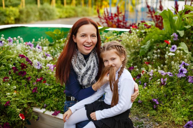 Smiling mother sitting in park with young blonde daughter