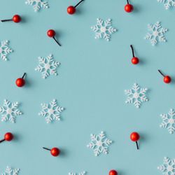 Christmas pattern made of snowflakes and red berries on blue background
