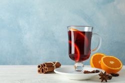 Mulled wine, orange and cinnamon on blue wooden background, space for text