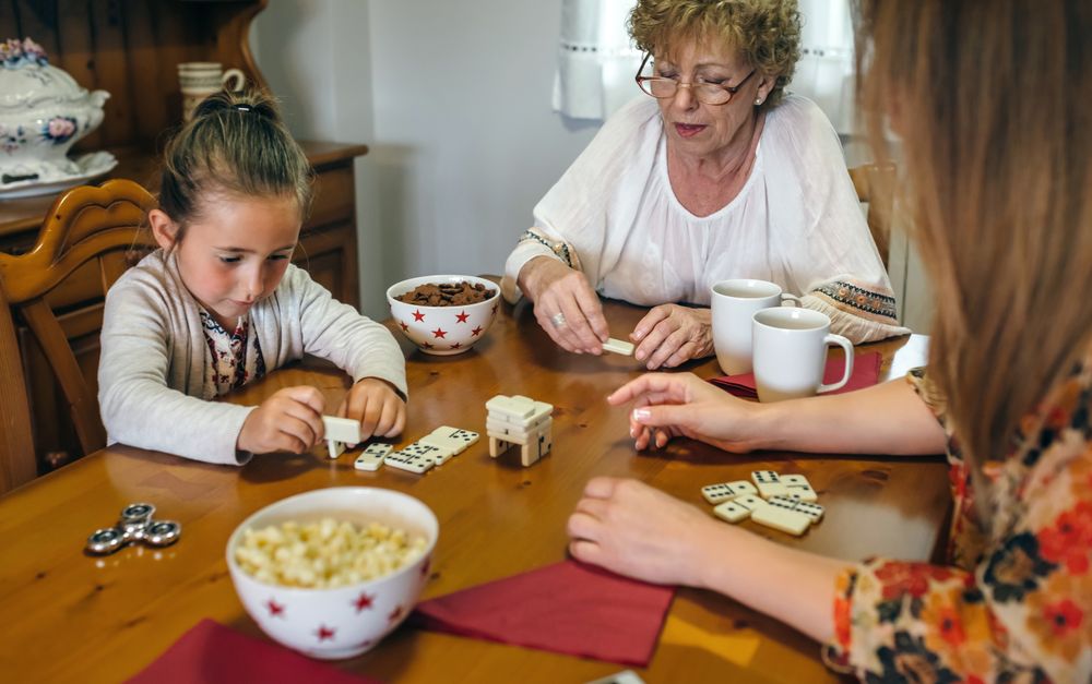 Three female generations playing with dominoes