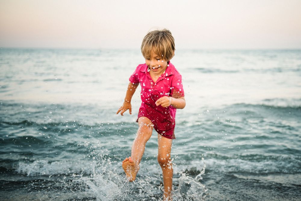 Playful boy splashing water on coast