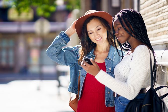Female friends both calmly looking down at a cell phone