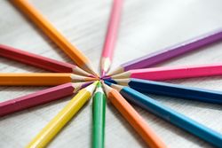 Coloured pencils arranged in a circle on a wooden background