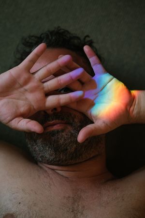 Bearded man covering eyes from rainbow glare