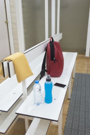 Empty changing rooms with backpack and drinks on bench, vertical composition