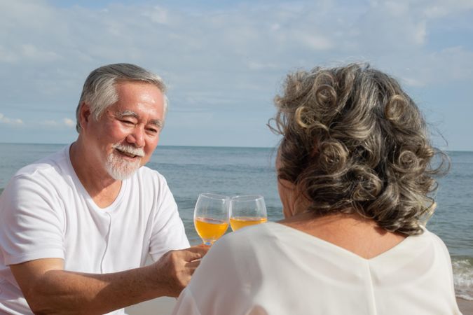 Older Asian couple relaxing at the waterfront with wine