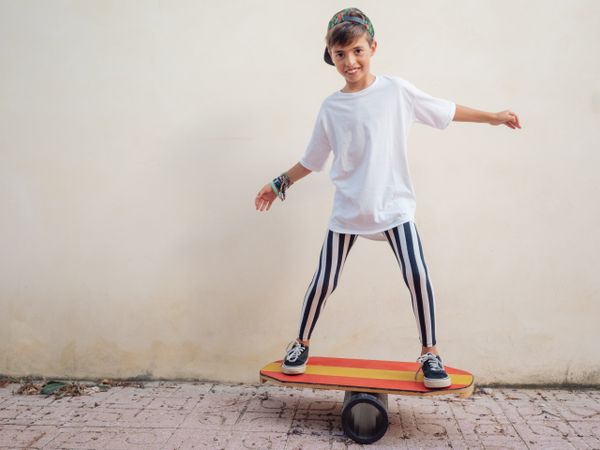 Cheeky boy standing on colorful board and swinging