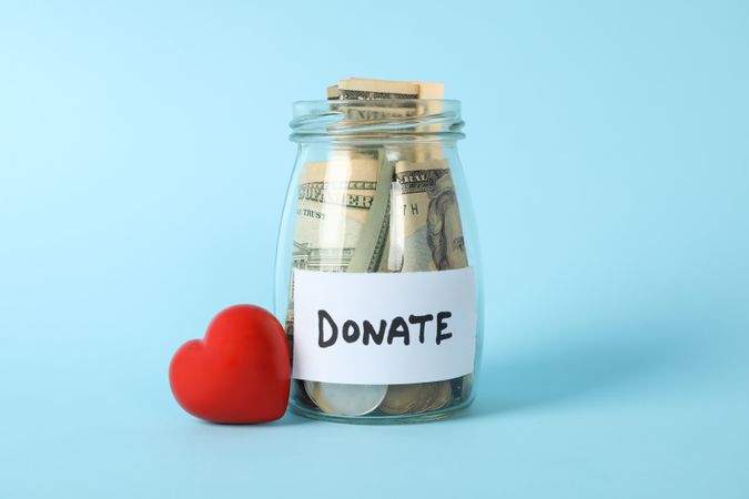 Glass jar with text Donate and heart on blue background