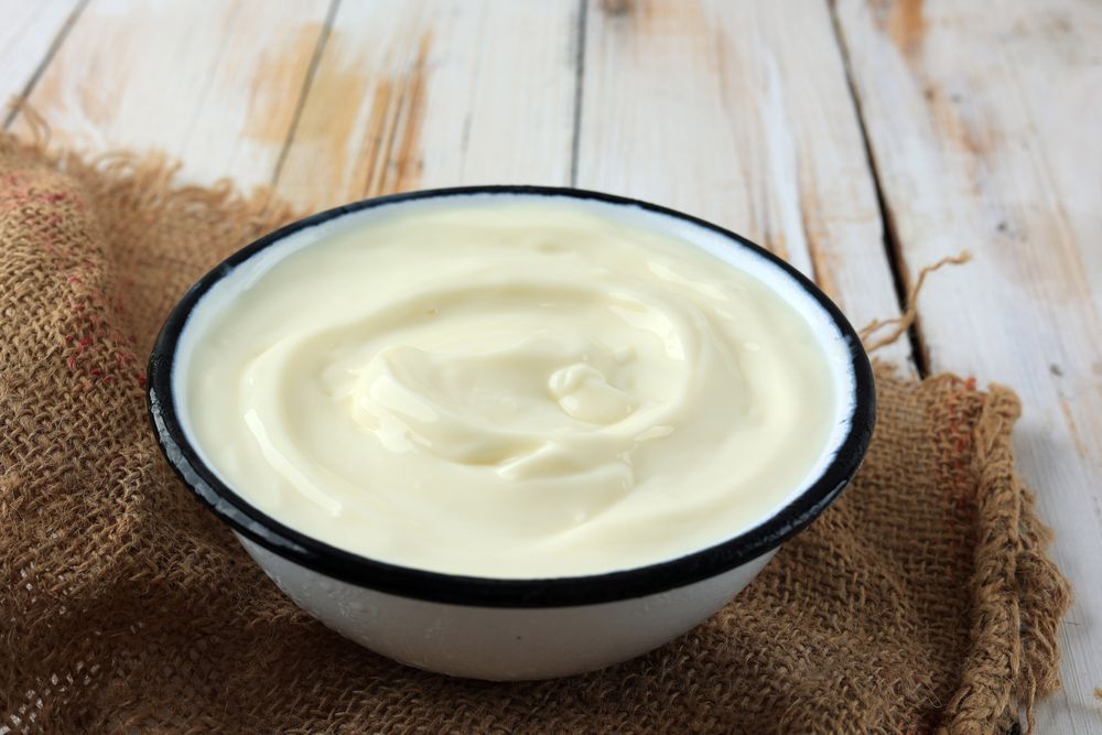 Greek Yogurt in a Enamel Bowl with on Rustic Wooden Plate.