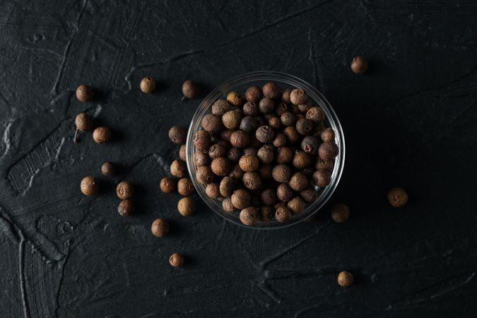 Top view of glass bowl with peppercorns on dark background