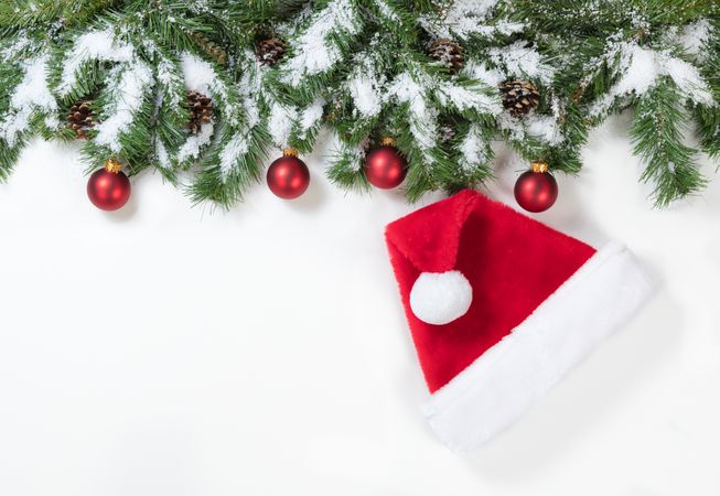 Snowy Christmas branches with Santa Claus hat and red ornaments