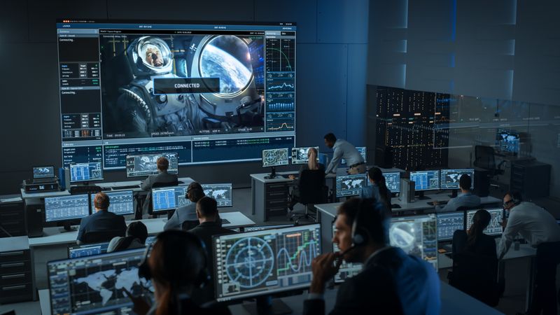 Mission Control Center Monitors Spacewalk. Large Screen Shows Astronaut With Earth View.