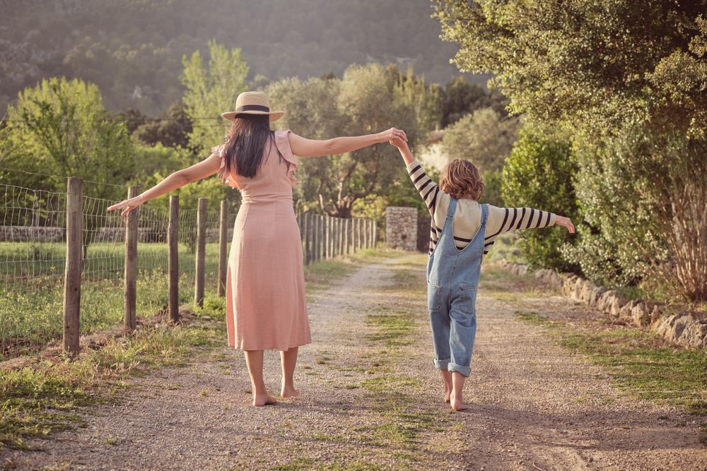 Woman with son holding hands walking in park