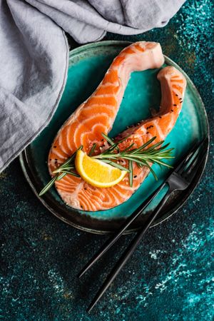 Top view of salmon fish with rosemary and lemon on counter with copy space